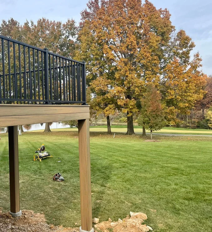 Wooden deck with black aluminum fencing and trees behind.