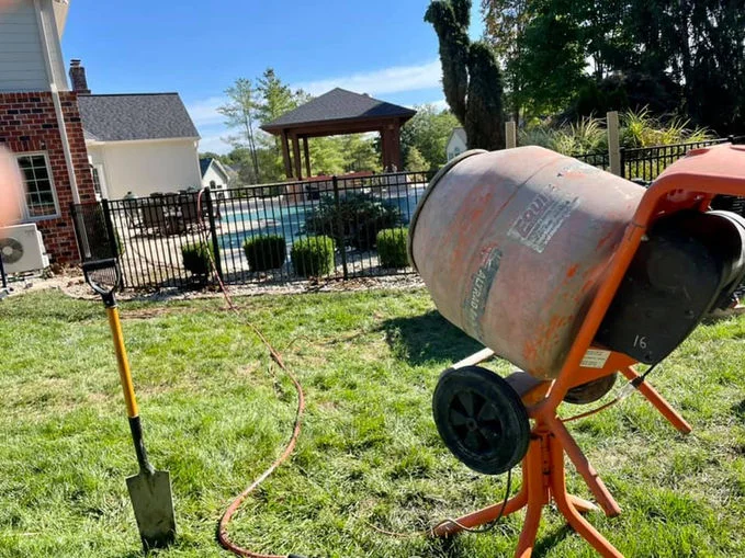 Black aluminum fence behind concrete mixer.