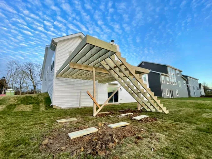 Wooden decking near house with white siding.