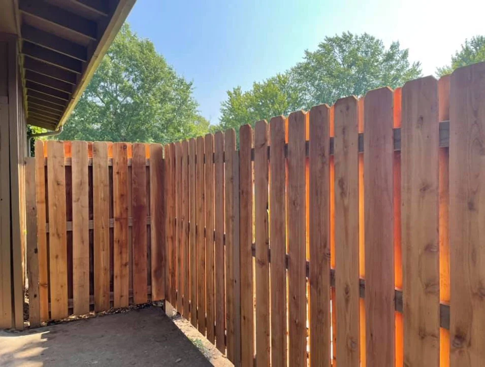 Wooden fence with trees behind it.